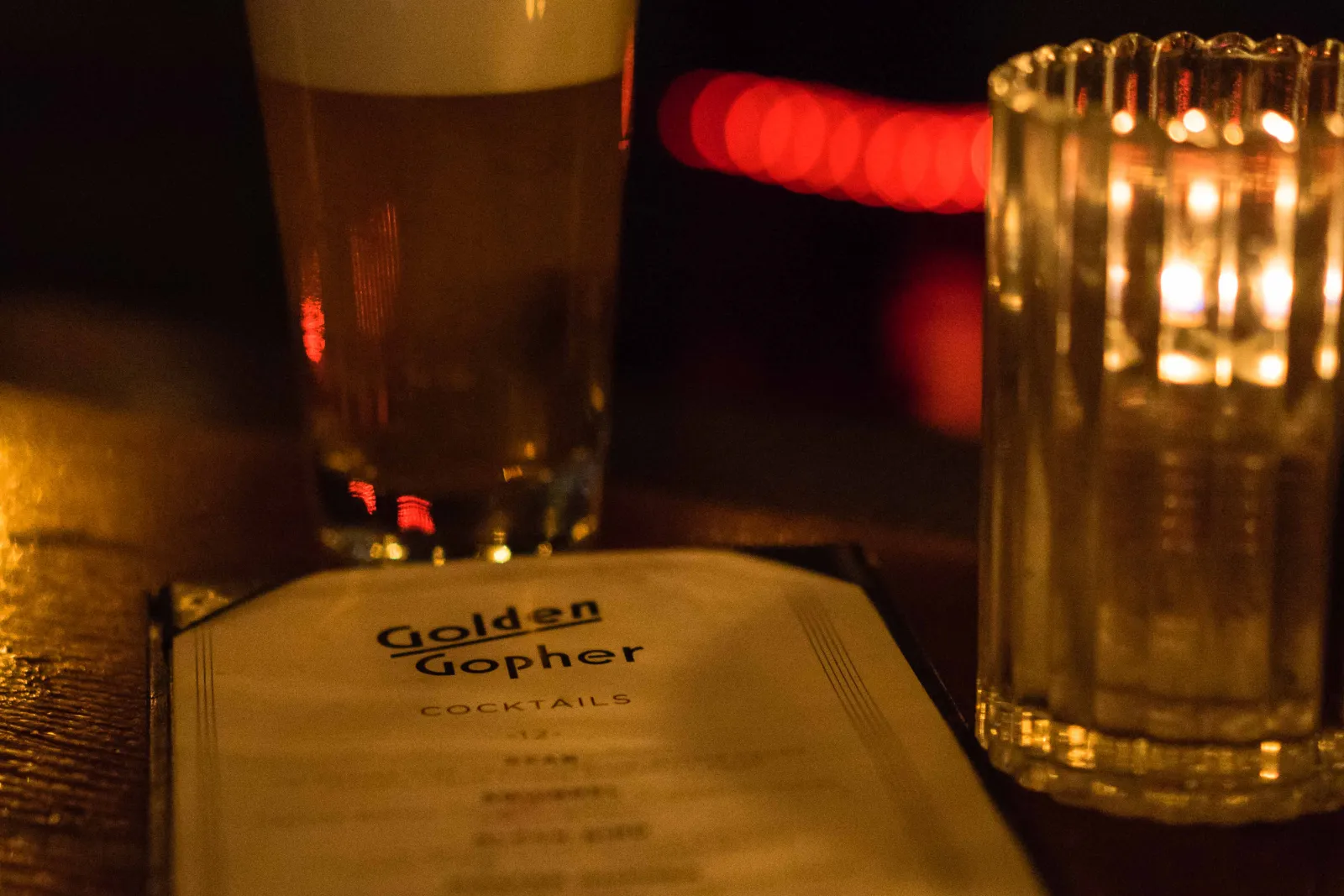 A cold beer and the cocktail menu on the bar