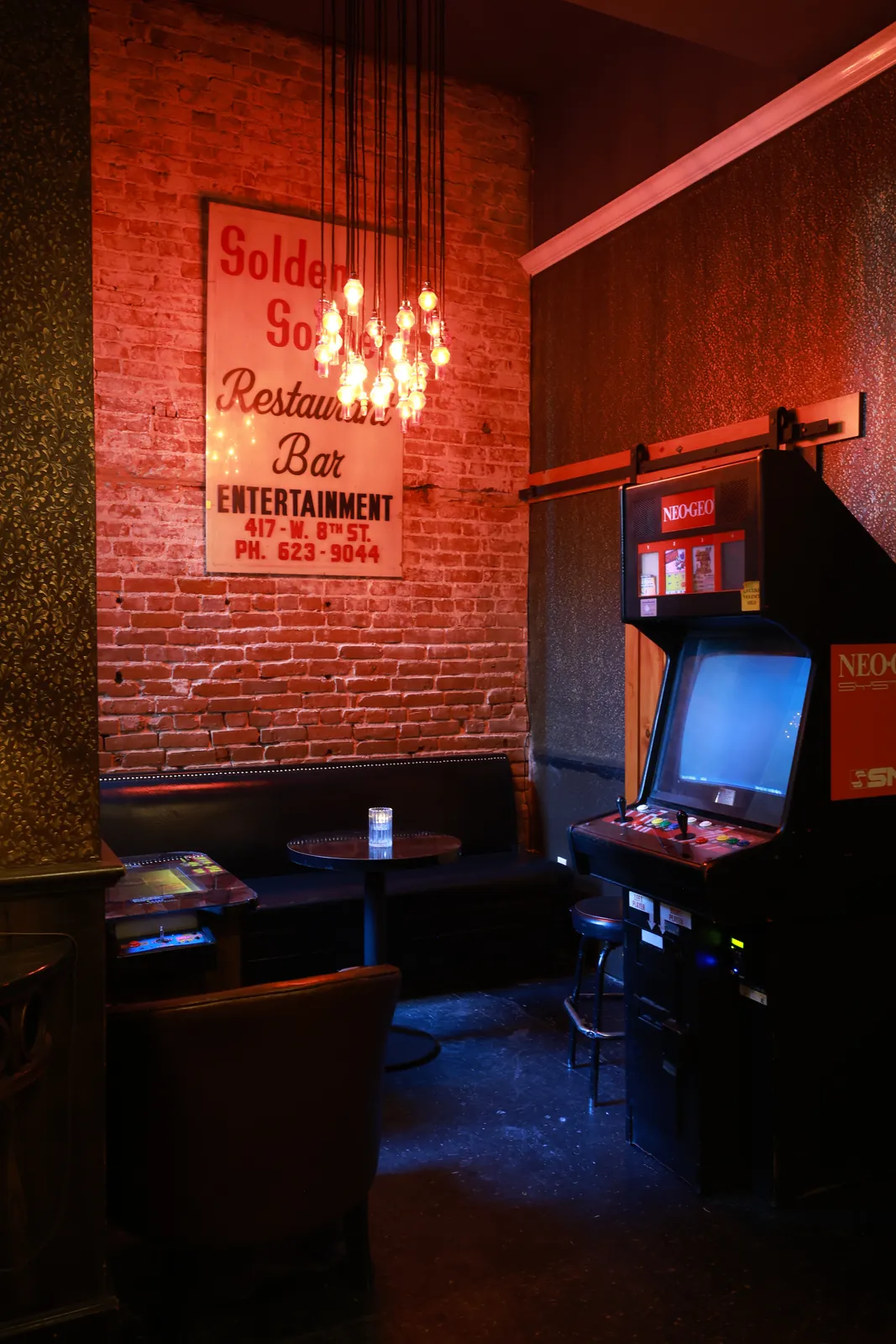 A vintage arcade cabinet in the back corner under the old Golden Gopher sign