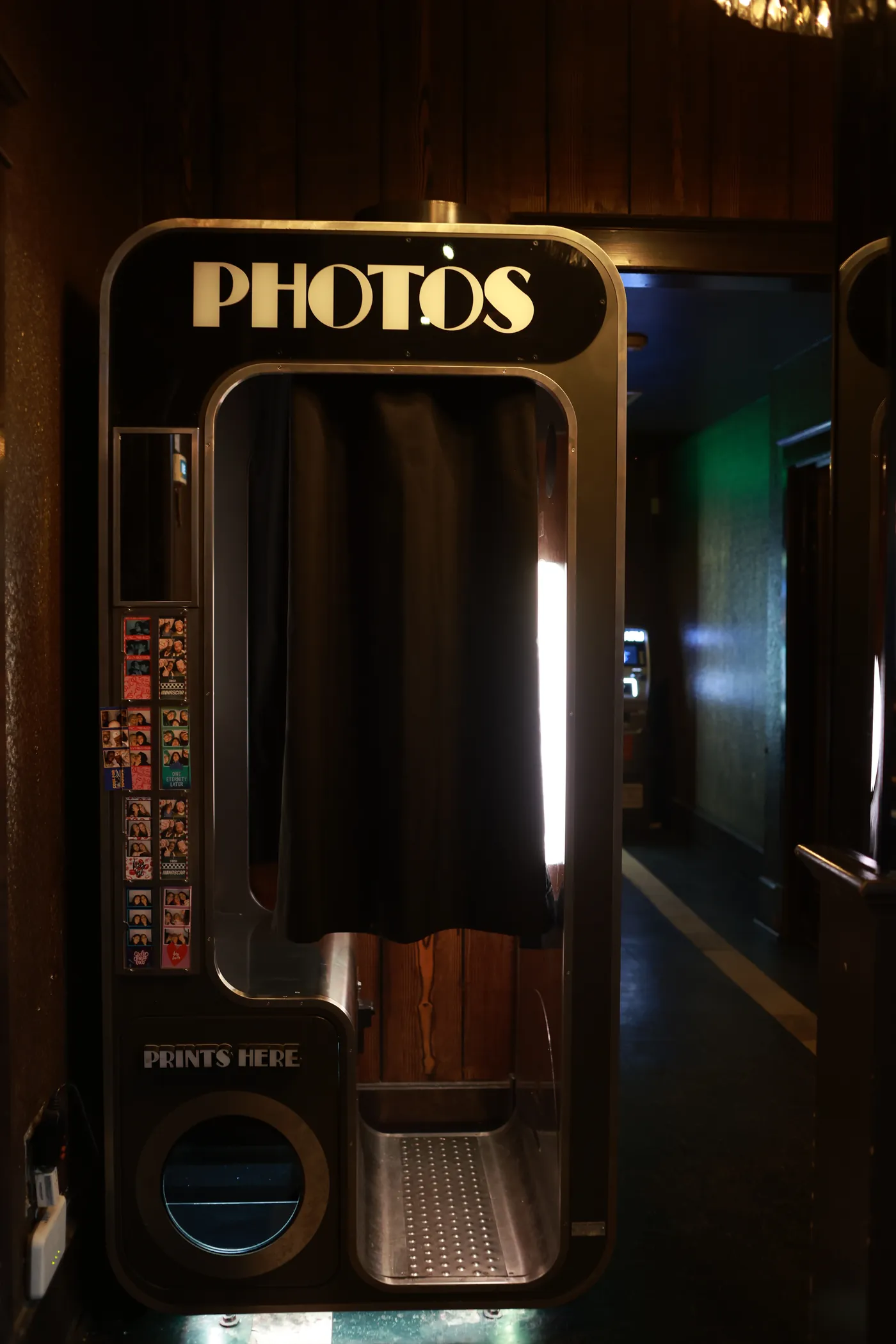 The photo booth, a gold-trimmed cabinet with PHOTOS across the top and a black curtain